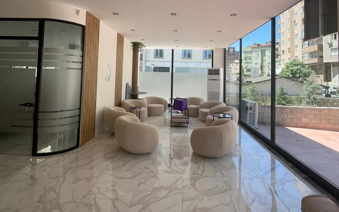 Geniş cam cepheli bekleme salonu, açık renkli oturma grupları